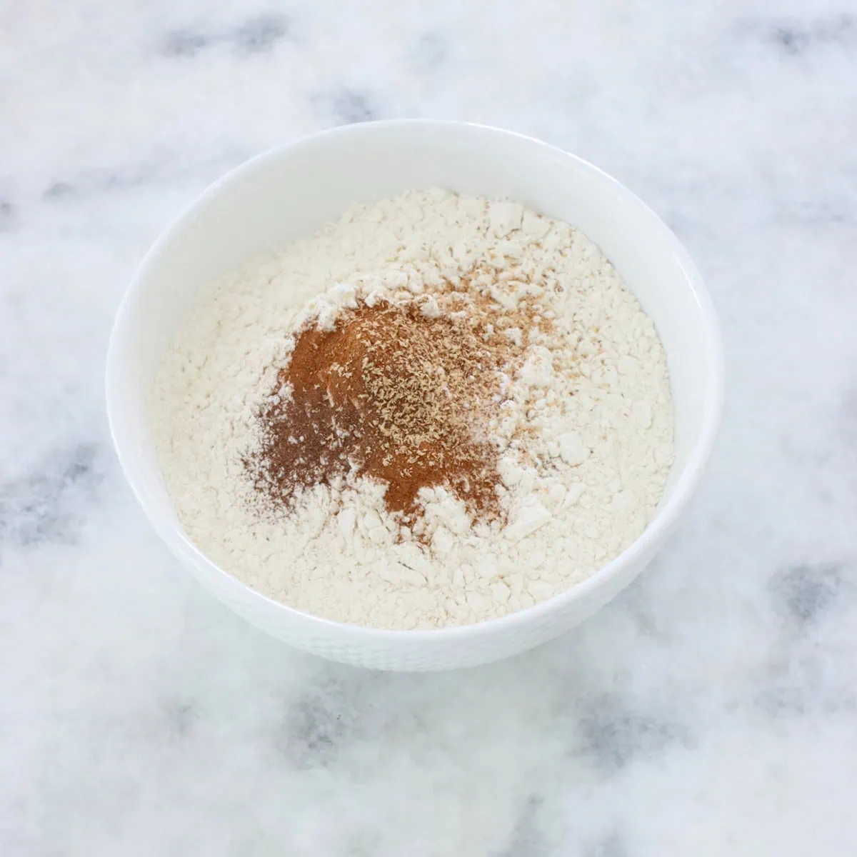 Mixing dry ingredients in a separate bowl, flour, baking powder and soda, cinnamon, nutmeg and allspice. 