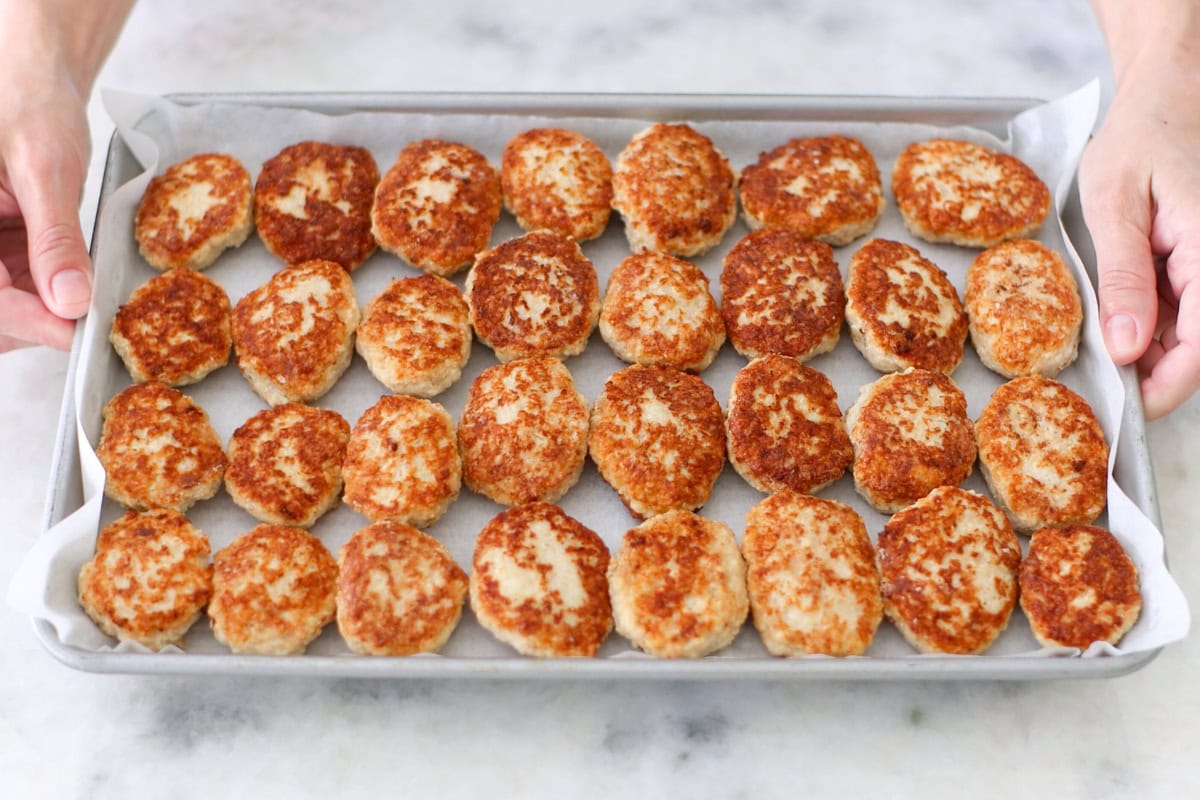 Chicken kotleti in a single layer on a baking sheet for freezer meal prep. 