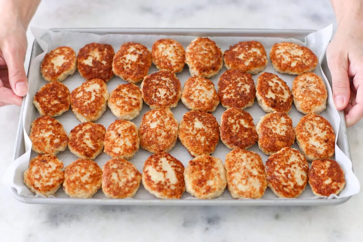 Chicken kotleti in a single layer on a baking sheet for freezer meal prep. 