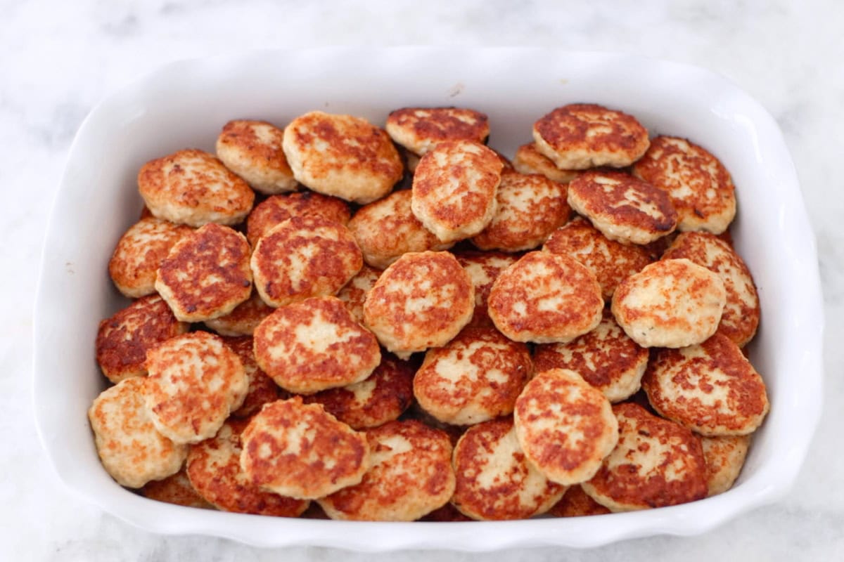 A large batch of chicken kotleti for meal prep in a baking pan. 