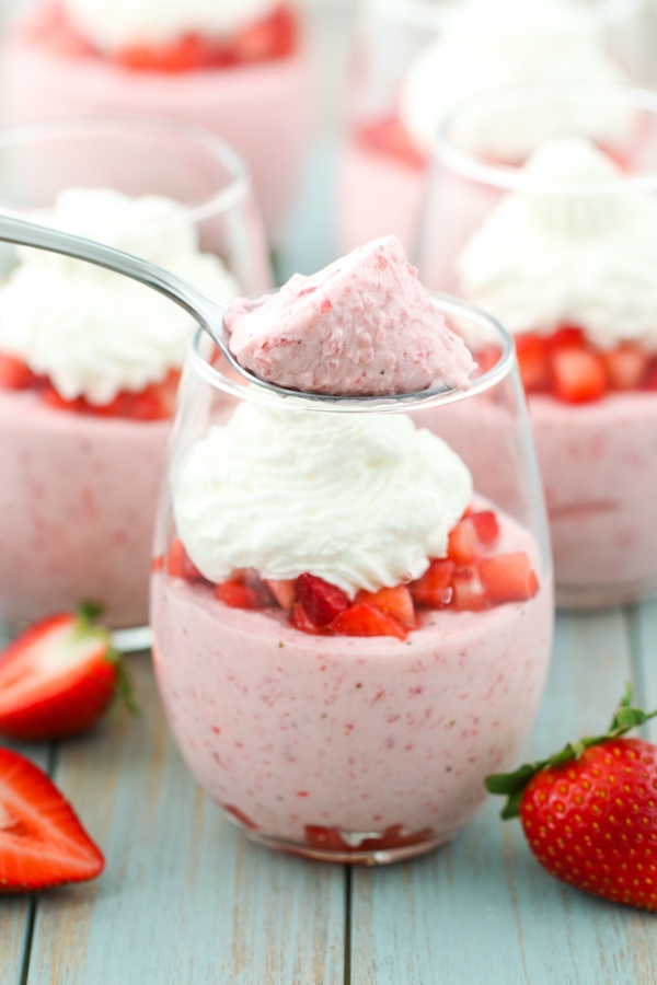 A spoonful of luscious and fluffy strawberry mousse in an individual serving with fresh strawberries and whipped cream. 