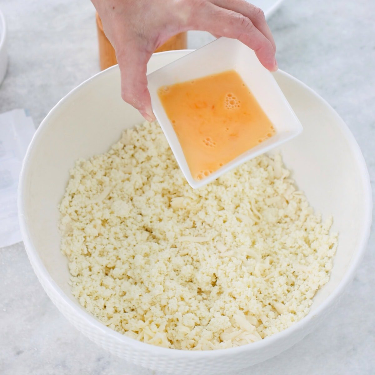 Farmer's cheese cookies process, pouring eggs into dough in a mixing bowl.