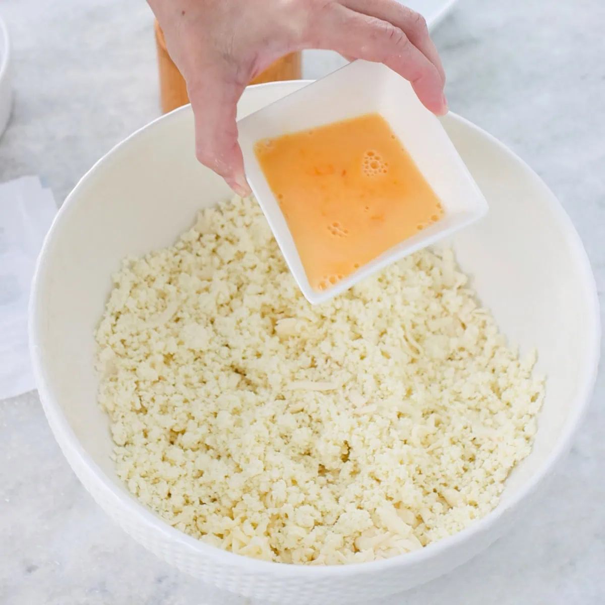 Farmer's cheese cookies process, pouring eggs into dough in a mixing bowl. 