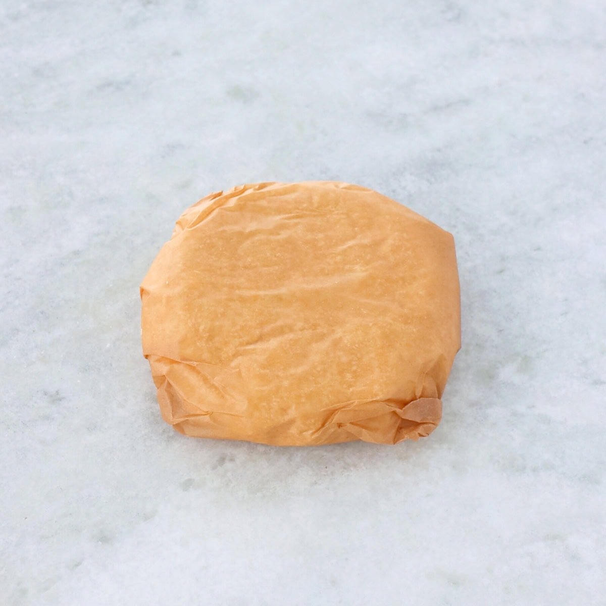 Cookie dough wrapped in parchment paper on the counter, ready to be chilled.