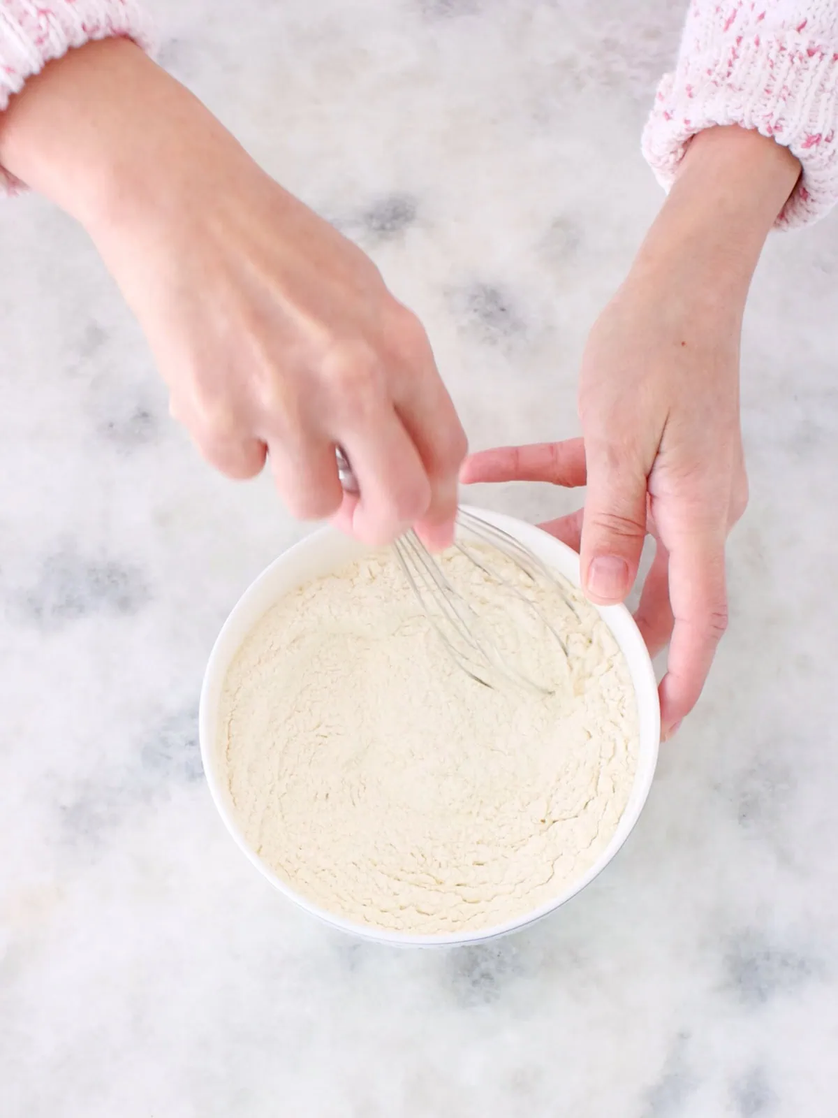Whisking dry ingredients together in a bowl, flour, baking powder, baking soda and salt.
