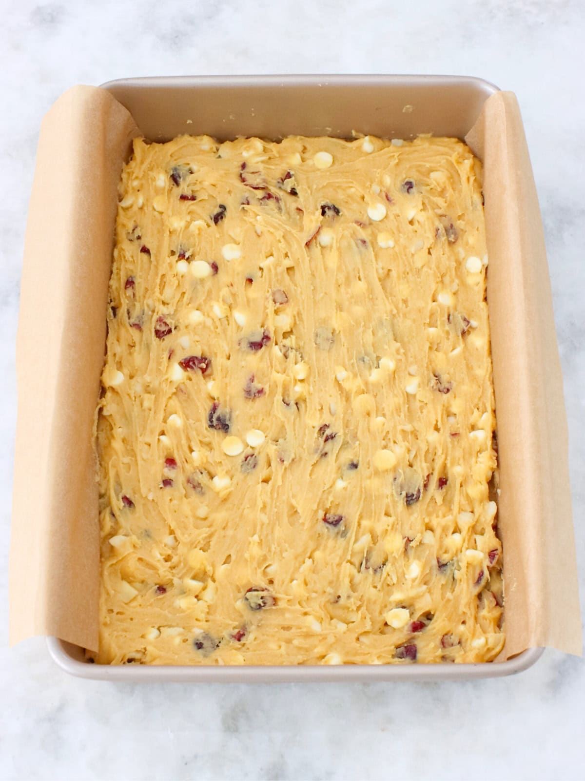 White chocolate and macadamia cookie bar batter spread out in a baking pan. 