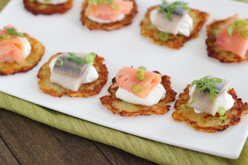 Potato Pancake appetizers with sour cream, smoked salmon, dill, green onions and herring. 