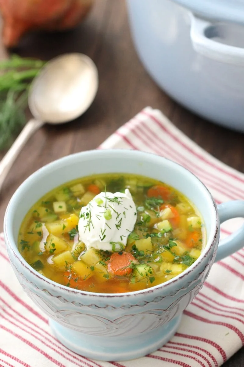 A bowl of Golden Beet Soup with a dollop of sour cream and fresh herbs. 