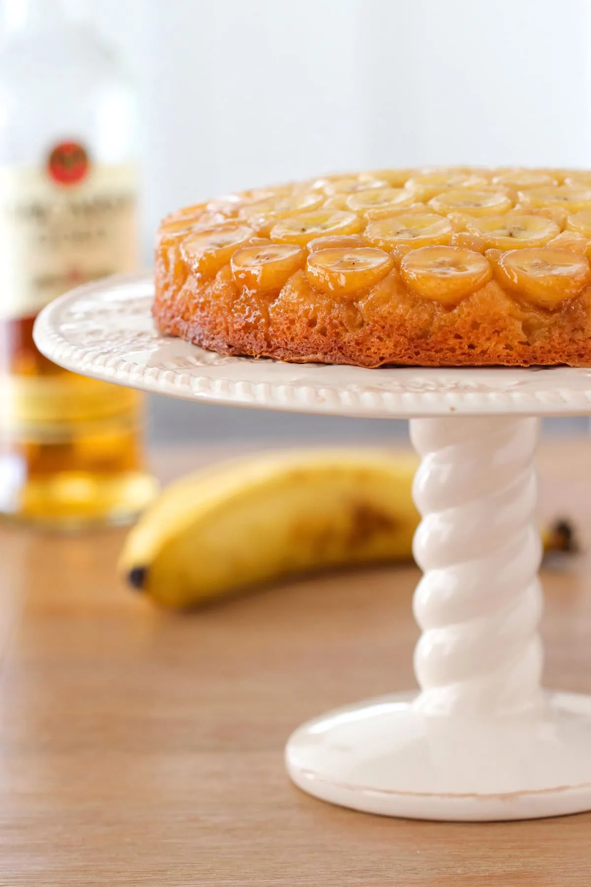 Banana Upside Down Cake on a cake stand. Caramelized bananas foster on top of the cake. 