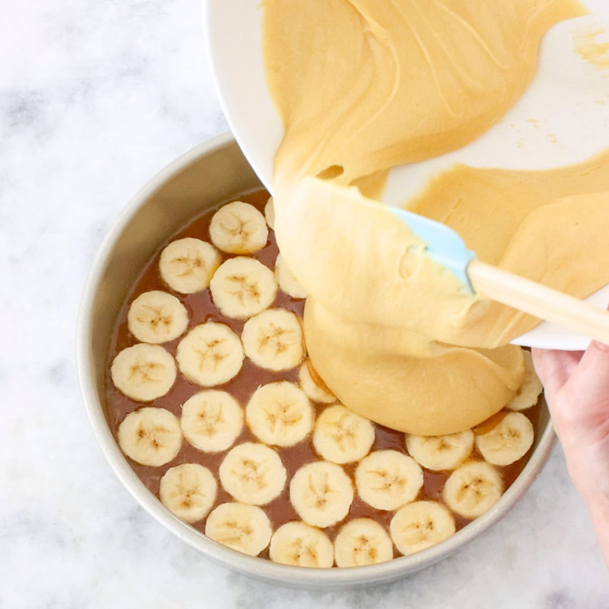 Banana upside down cake process, pouring batter over bananas.