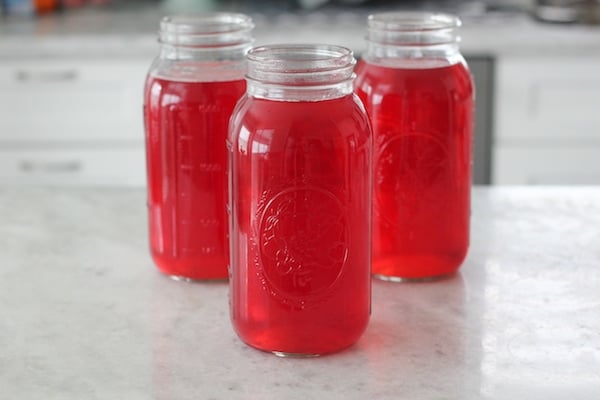 Cranberry Raspberry Kompot in glass mason jars on a counter. 