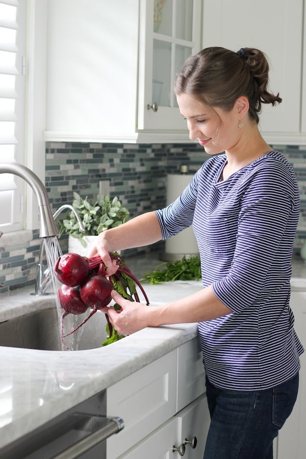 Olga, creator of Olga's Flavor Factory, washing beets in the sink in her home kitchen.