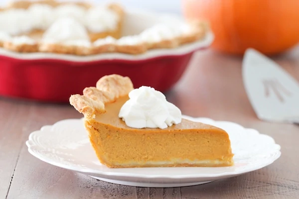 A slice of smooth and creamy pumpkin pie with whipped cream