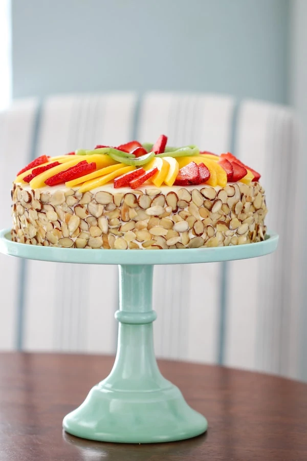 Fluffy Honey Layer Cake With Fruit and Almonds on a cake stand