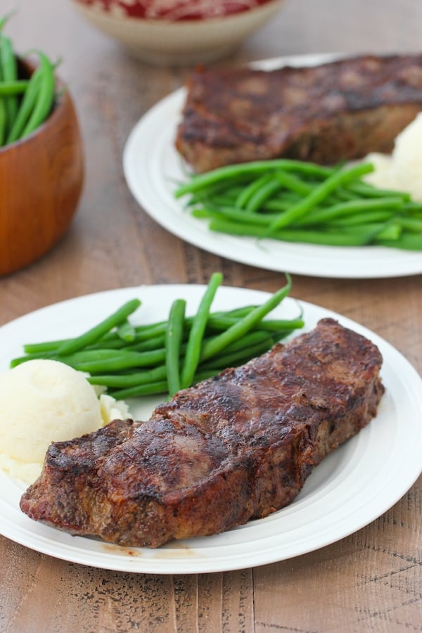 Perfectly grilled steak with grill marks on a plate with mashed potatoes and green beans