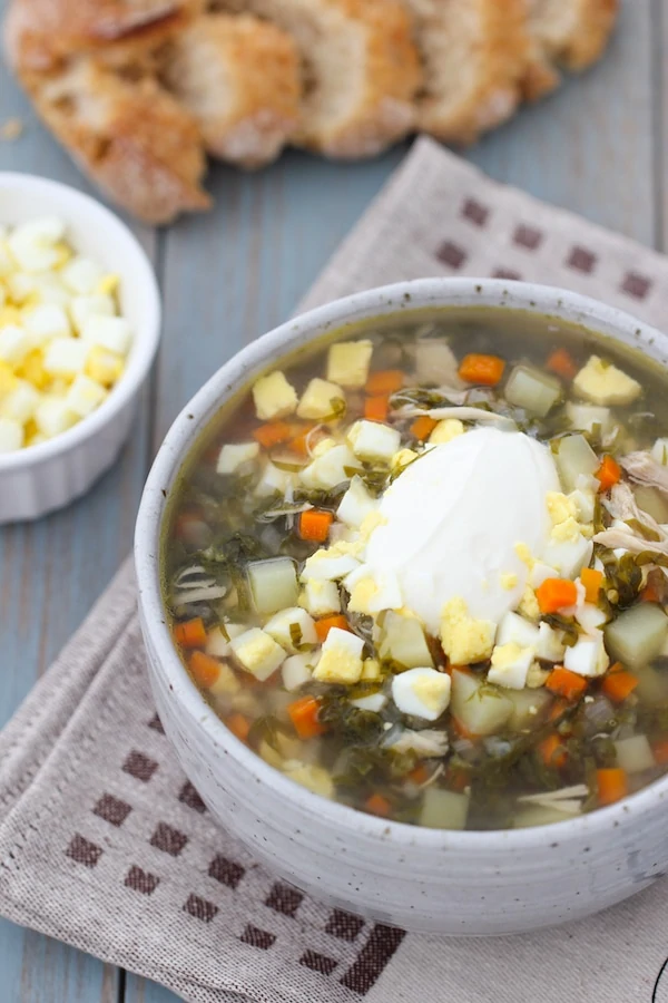 A bowl of Green Borsch; a sorrel soup made with potatoes, onions, carrots and garnished with hard boiled eggs and sour cream. 