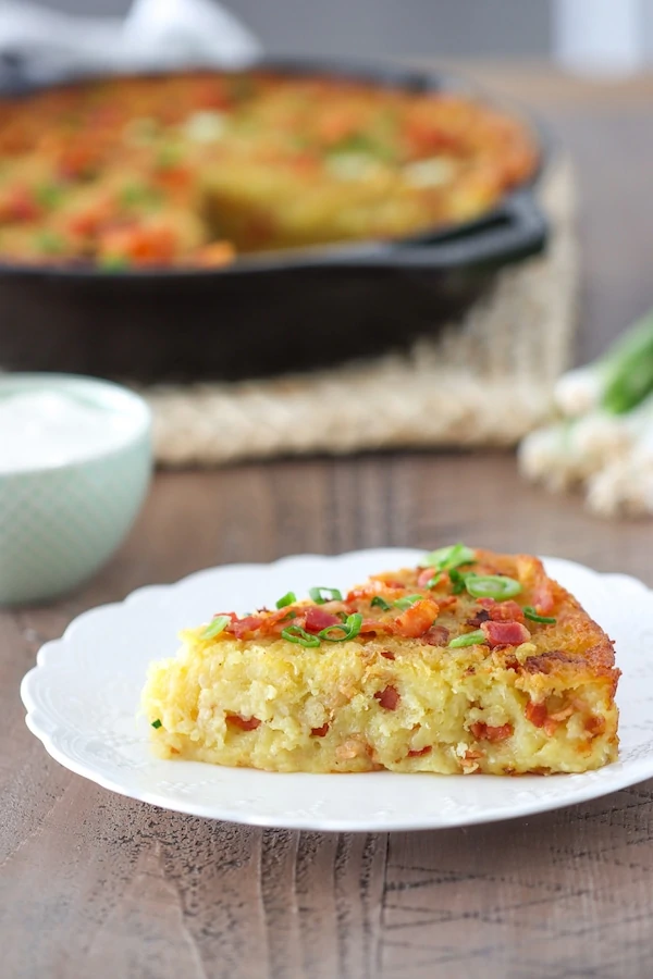 Belarusian Pototo Babka, a potato casserole or potato cake made with grated raw potatoes, sautéed bacon and onions. It's golden and crisp on the outside and tender and fluffy on the inside, served with sour cream. 