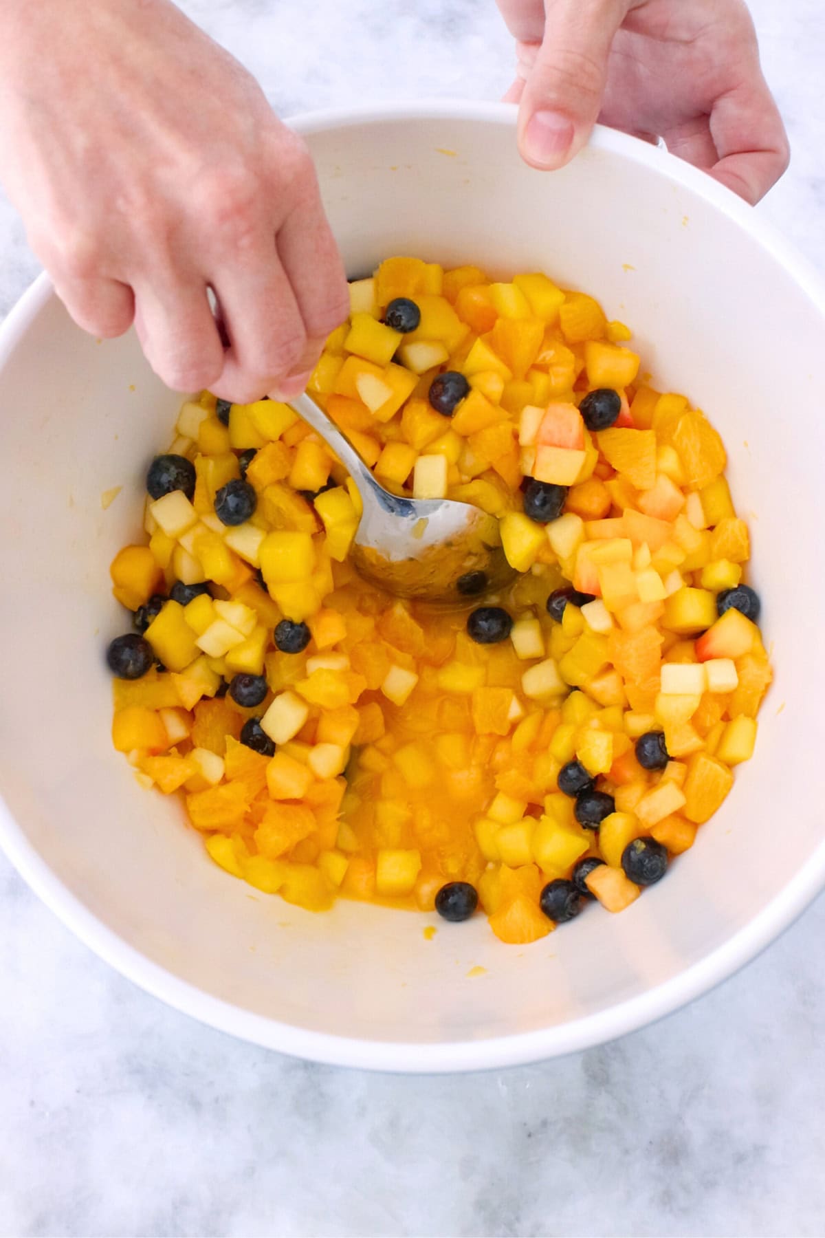 Make ahead fruit salad in a bowl with citrus syrup made tropical fruit and blueberries.