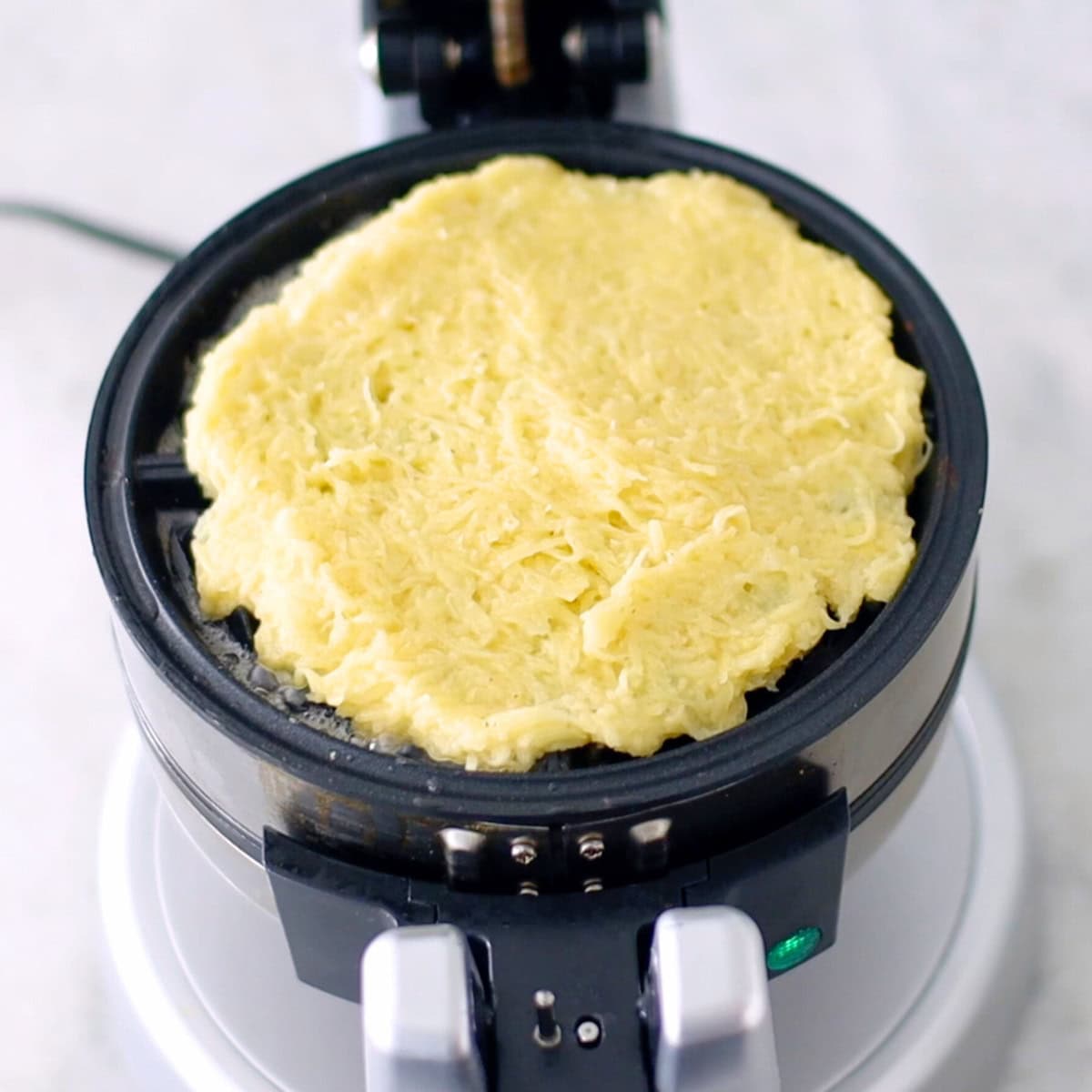 Potato waffles, batter spread out in waffle maker. 
