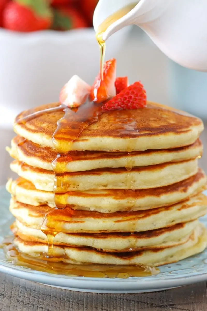 The most tender and fluffy buttermilk pancakes with strawberries and maple syrup. 