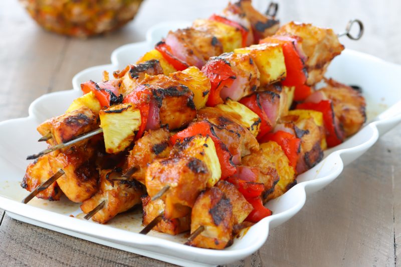 A plate of teriyaki chicken kabobs with pineapple, bell peppers and red onion. 