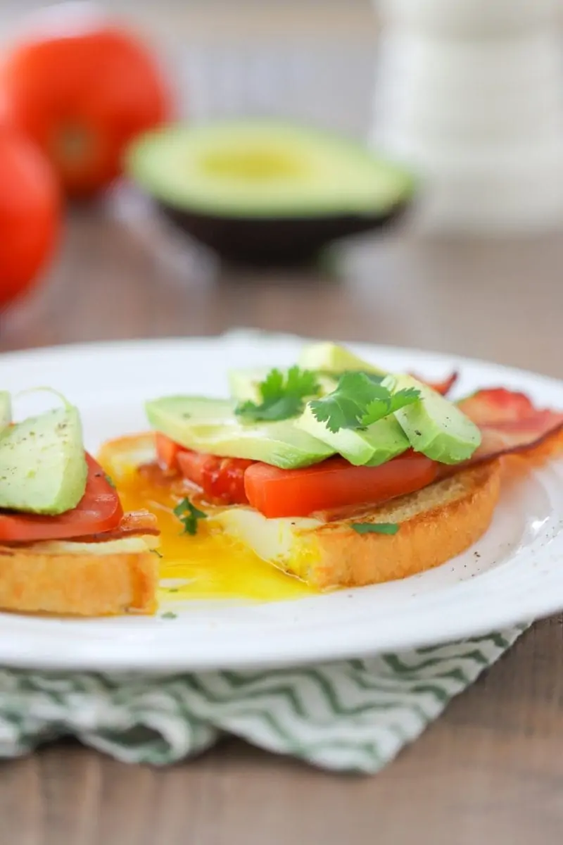Egg in a hole breakfast sandwich with bacon, tomatoes and avocados.