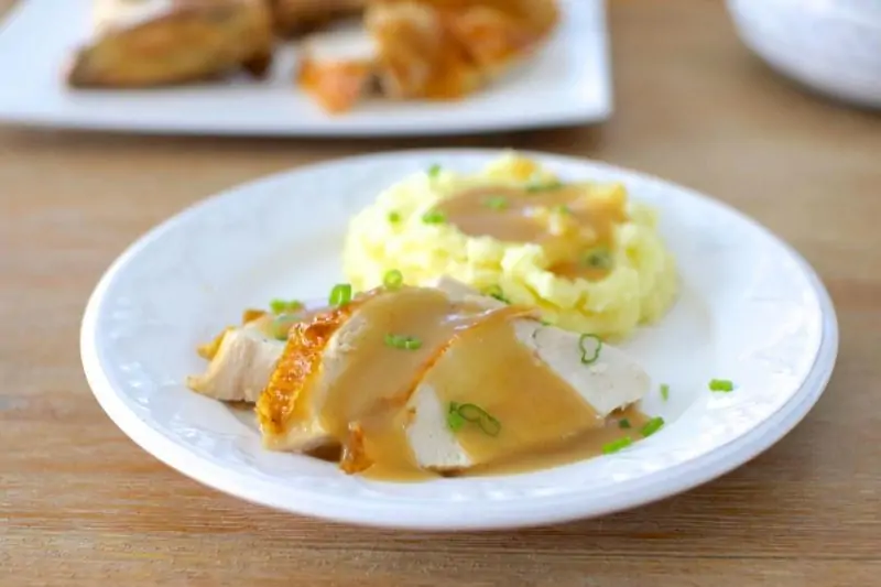 cast iron roast chicken with gravy on a plate with mashed potatoes