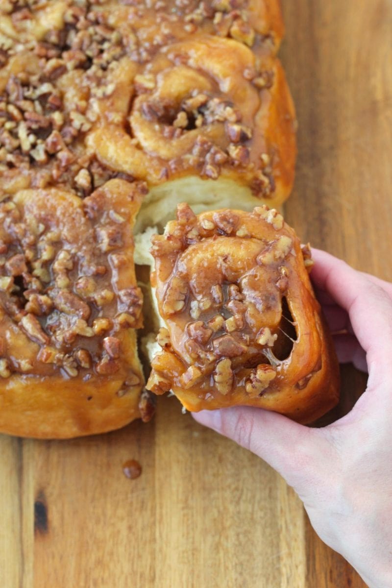 Pulling apart the Pecan Sticky Buns with a gooey topping. 