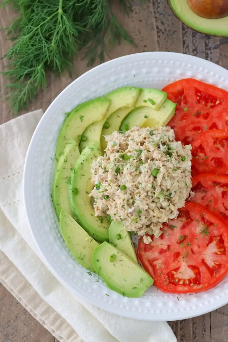 Easy Tuna Salad Recipe with hard boiled egg, celery, green onion and dill, served with tomatoes and avocados.