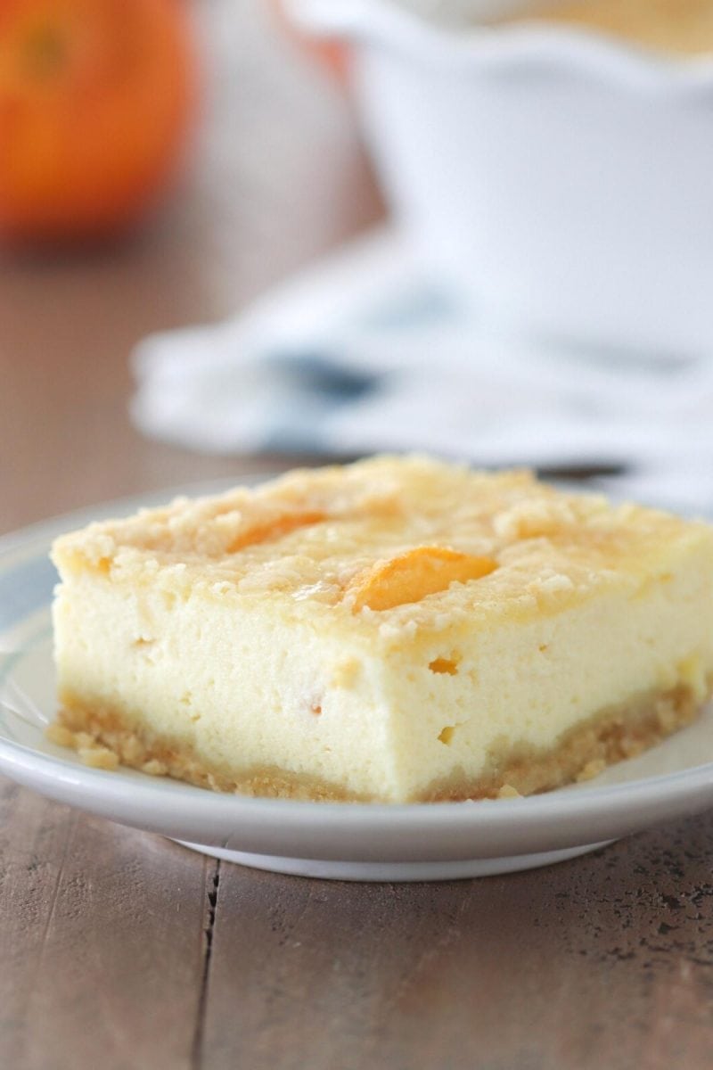 Ricotta Cheesecake Bars - a close up picture of a slice with peaches and a crumb topping. 