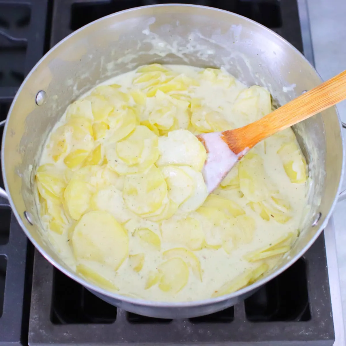 Thinly sliced potatoes cooking in cream for scalloped potatoes. 