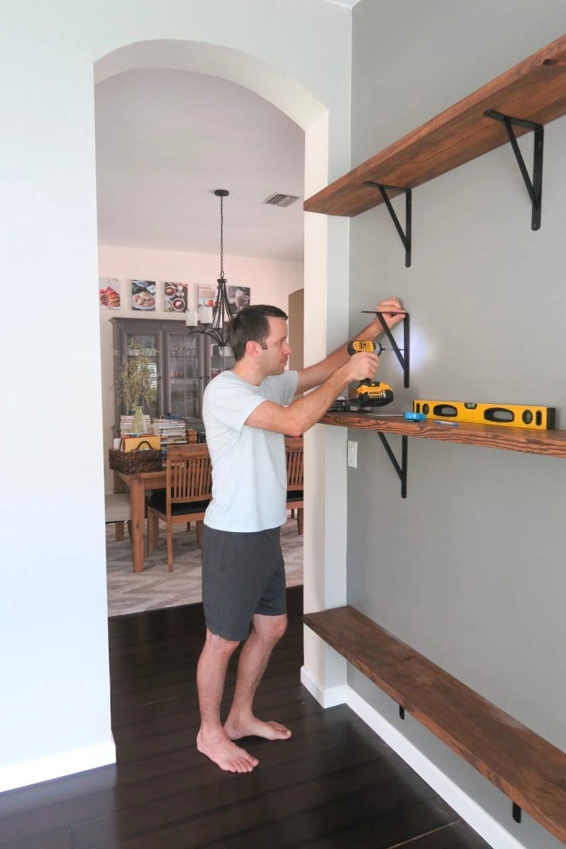 Installing brackets into the wall for diy home library shelves