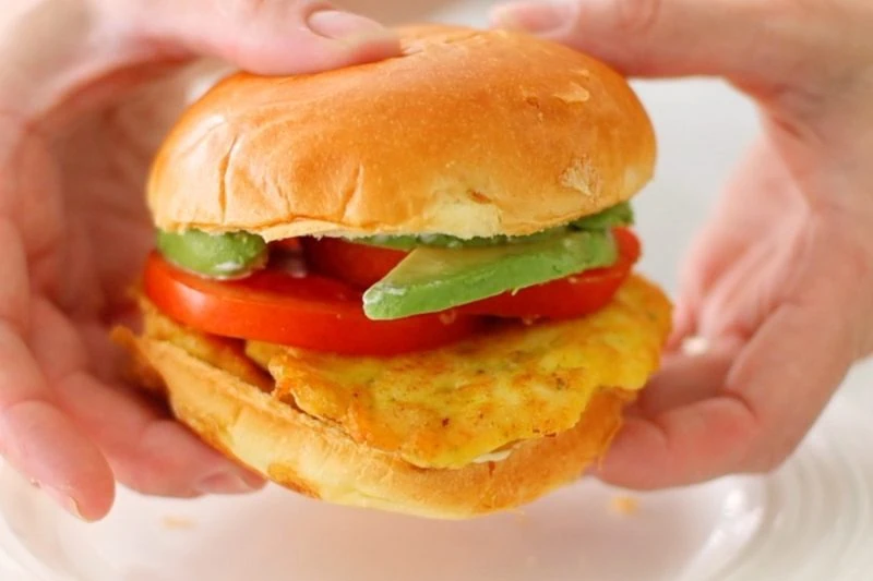 Chicken Fritter Sandwich on a brioche bun with tomatoes and avocados