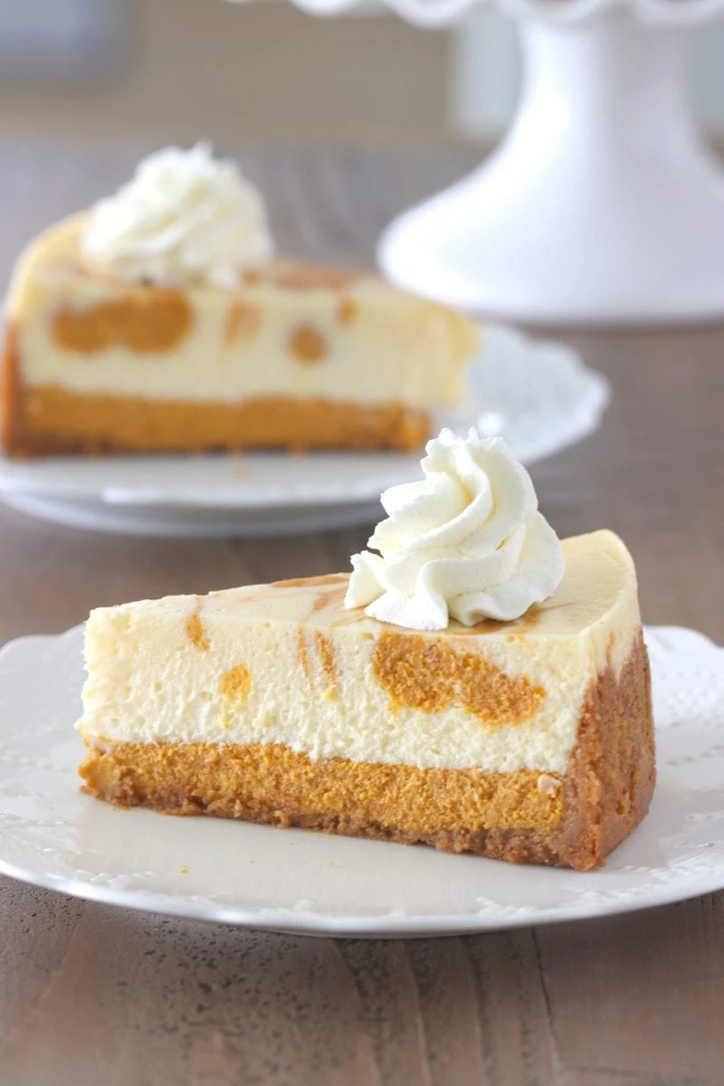 Pumpkin Swirl Cheesecake 
a slice of cheesecake with whipped cream on a plate