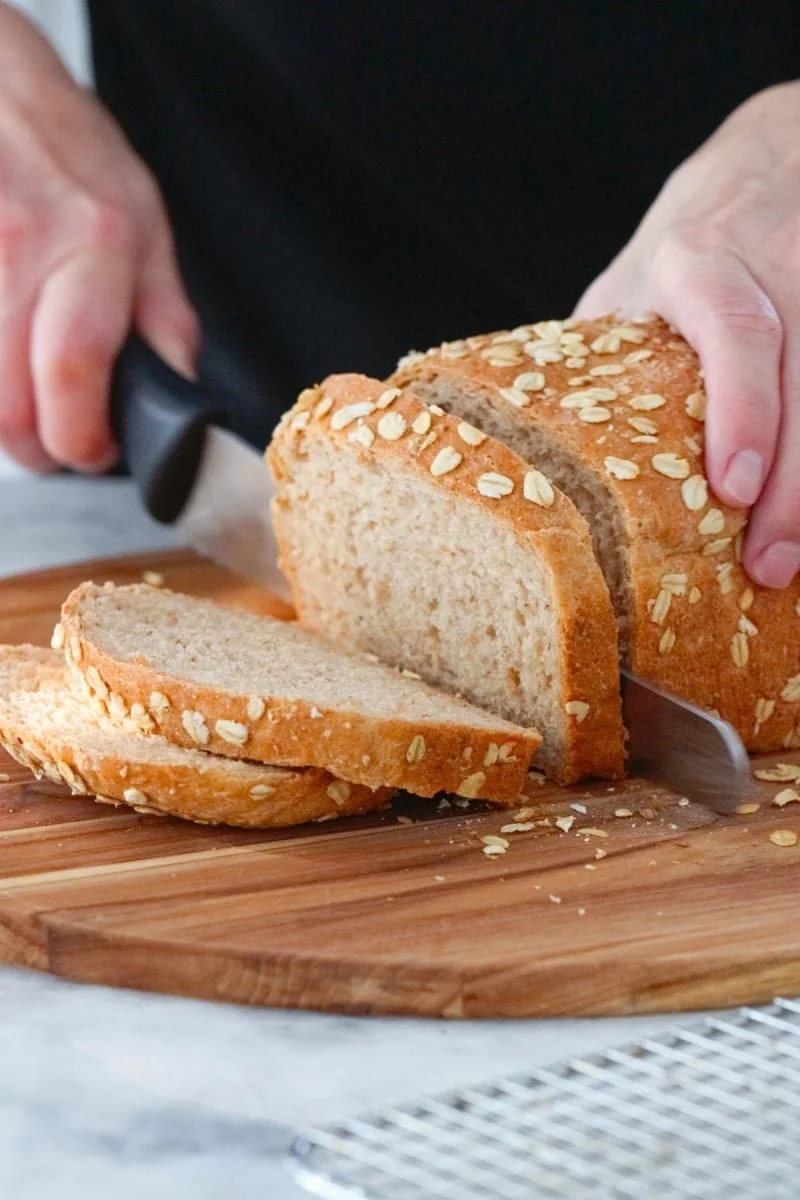 Slicing a loaf of multigrain bread with oatmeal