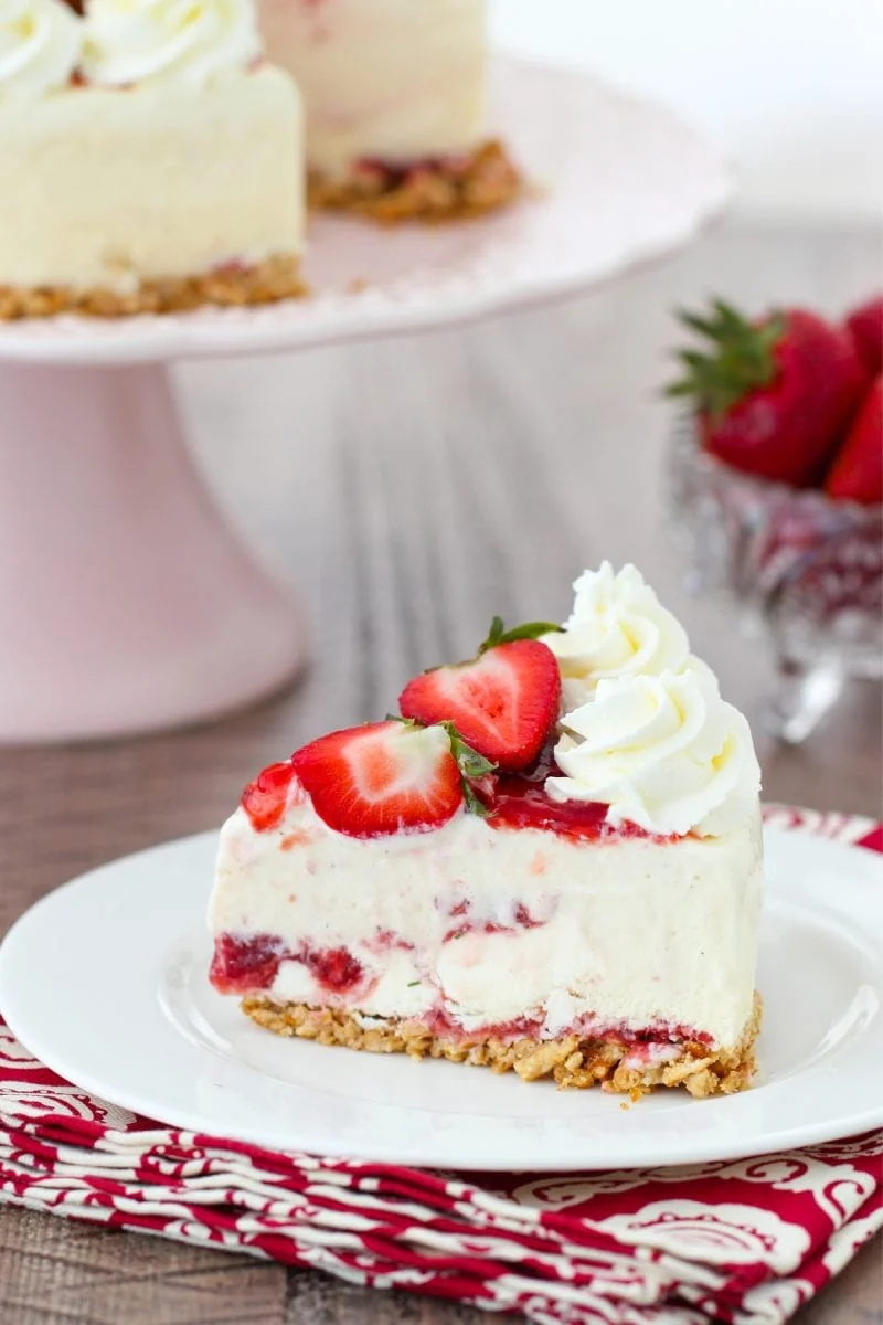 A slice of ice cream cake with strawberries, strawberry jam and a pretzel crust. 