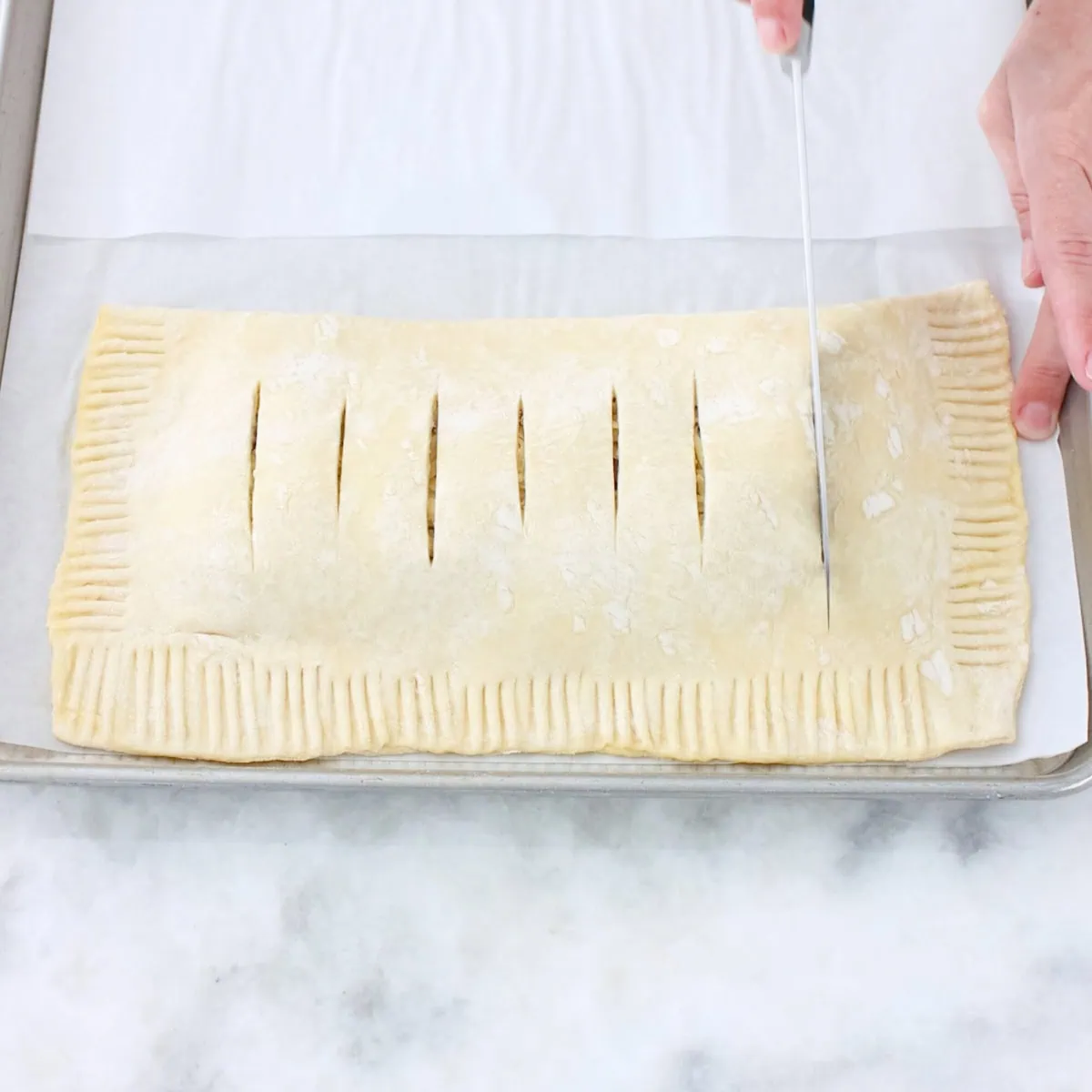 Potato bacon pastry, folded and sealed. Cutting slits with a knife on top of pastry. 