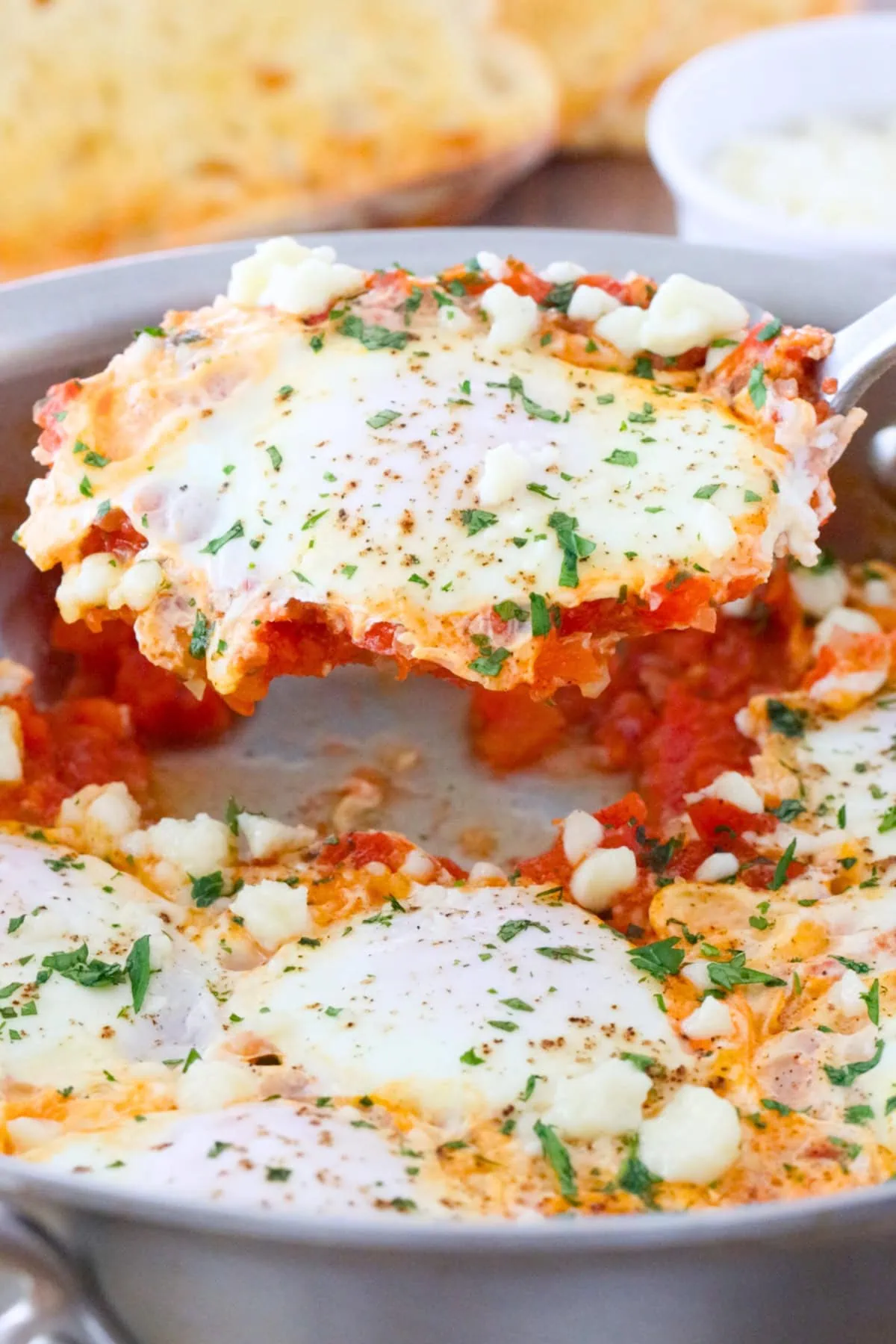Shakshuka with Fresh Tomatoes in a skillet, sprinkled with crumbled cheese and fresh herbs. 