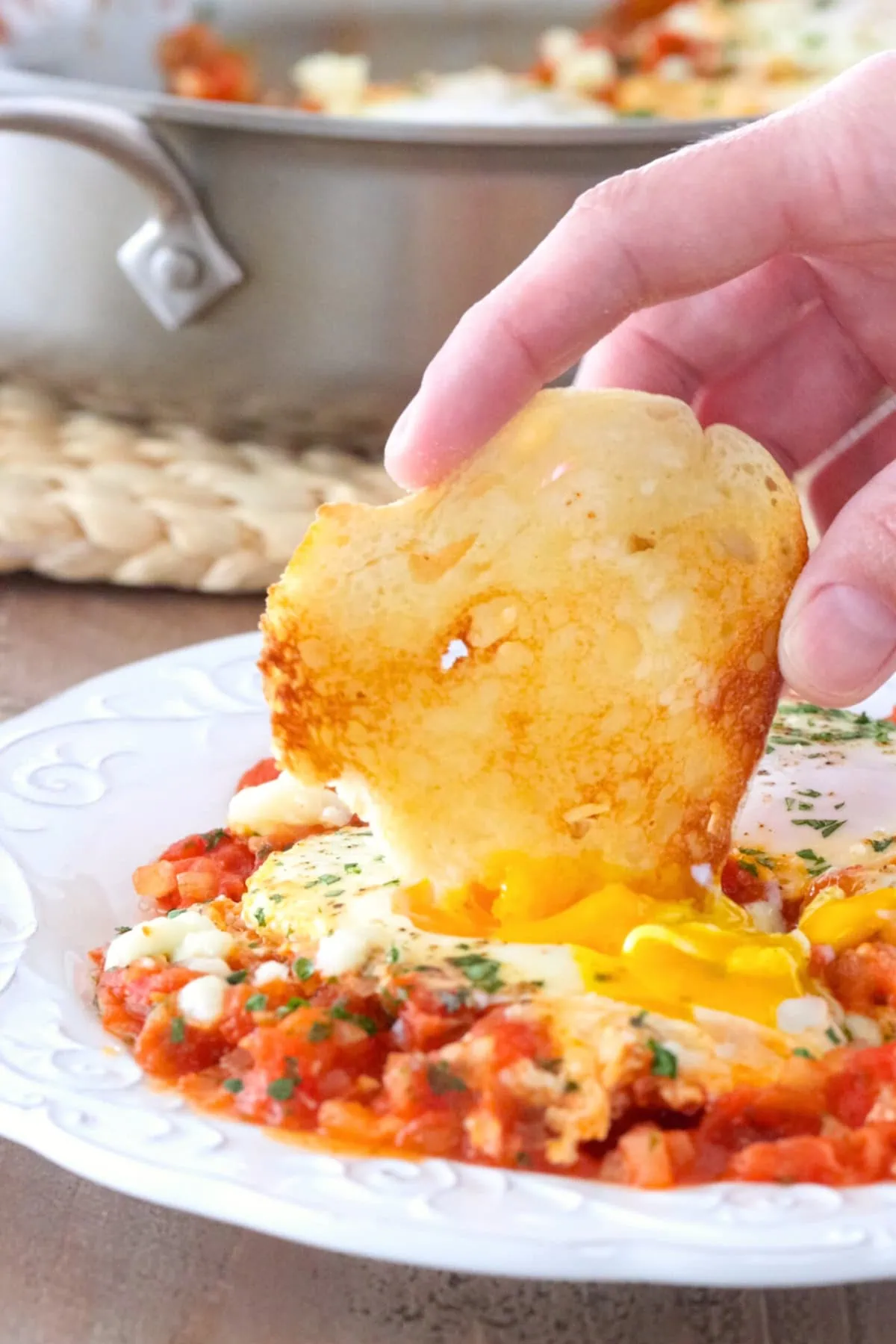 Shakshuka with fresh tomatoes on a plate served with toast dipped into the yolk. 