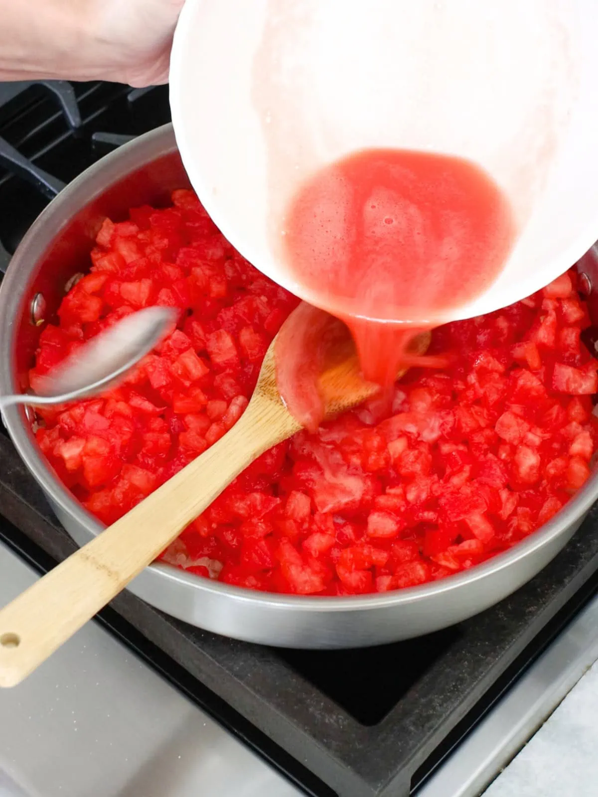 Fresh chopped tomatoes and tomato juice added to a deep skillet. 