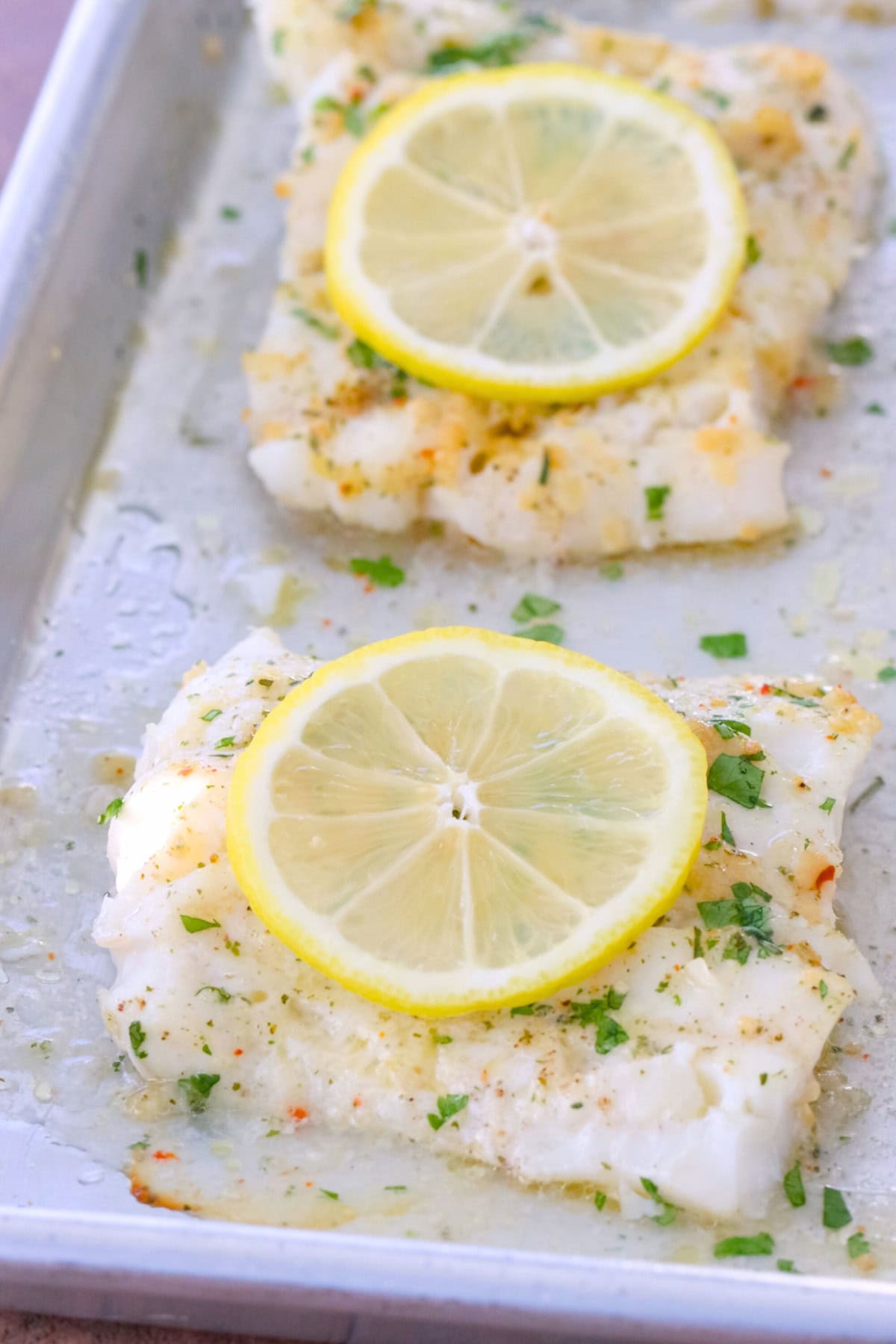 Lemon Garlic Baked Cod on a sheet pan, with a slice of lemon.
