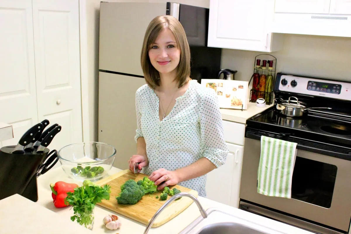 Olga cooking in apartment prepping vegetables. 
